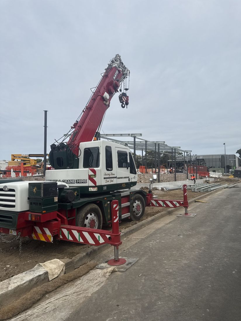 City crane set up on outriggers beside a steel frame