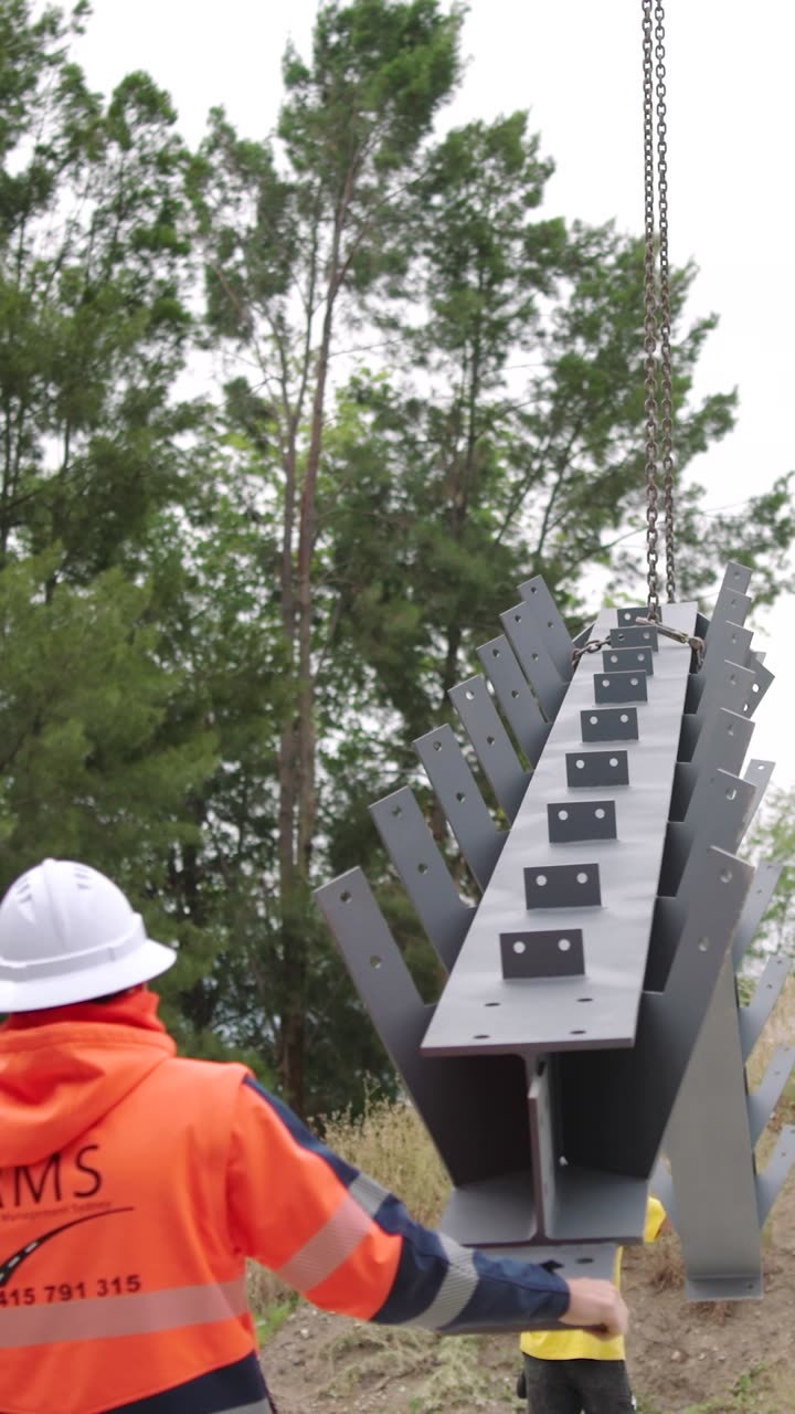 Rigger guiding a steel column as it is lifted